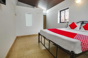 um quarto com uma cama grande e almofadas vermelhas em OYO Pratisha Guest House em Baga