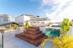 a balcony with a swimming pool and wooden stairs at Casa em resort, beira mar, 4 suítes, piscinas in Parnamirim