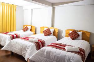 una camera con tre letti con lenzuola bianche di Inti kala lodge a Comunidad Yumani