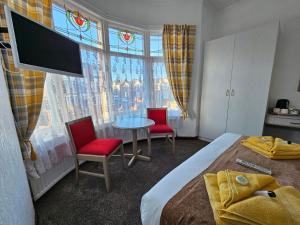 a bedroom with a bed and two chairs and a table at Collingwood Hotel in Blackpool
