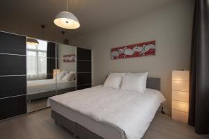 a bedroom with a large white bed and a mirror at Savina City Centre Apartment Near Beach, Station and Shops in Zandvoort