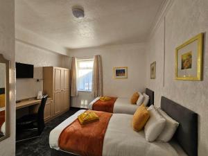 a hotel room with two beds and a desk at Collingwood Hotel in Blackpool
