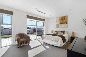 um quarto branco com uma cama e uma porta de vidro deslizante em 52 Esplanade - BYO Linen - Luxury - Seafront - Wi-Fi em Middleton