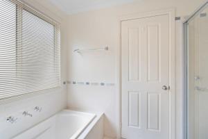 a white bathroom with a tub and a window at Encounters by the Sea 20 Whalers Rd Encounter Bay - BYO Linen in Encounter Bay +24 photos