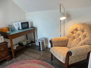 a living room with a chair and a microwave at Bryntirion Farmhouse Rooms (with bathroom) in Llanfair Caereinion