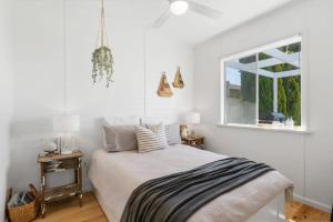 um quarto branco com uma cama e uma janela em On Birchall - Main House and Bunk House - BYO Linen em Goolwa