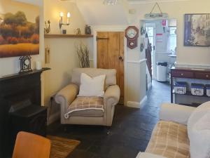 a living room with a chair and a clock at Tanners Cottage in Cockermouth