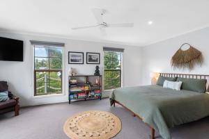 a bedroom with a bed and a couch and windows at Shanti - 4 Channon St Port Elliot BYO Linen in Port Elliot