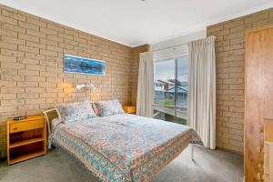 埃利奥特港Knights View - 2 14 Merrilli - BYO Linen - Wi-Fi - Beachfront的一间带床和砖墙的卧室