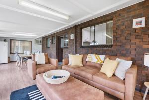 a living room with a couch and a brick wall at 58 Colman Rd Goolwa South - BYO Linen in Goolwa South