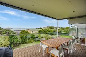 a wooden table and chairs on a deck with a view of the ocean at Encounter Bay Family Escape, Sea Views, Games Room & Walk to The Bluff in Encounter Bay