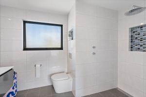 Un baño blanco con inodoro y ventana. en 1 Bowley Street Goolwa Beach - BYO Linen, en Goolwa South 30 fotos más