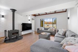 Una sala de estar con sofás, chimenea y televisión. en 1 Bowley Street Goolwa Beach - BYO Linen, en Goolwa South