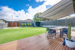 Una terraza de madera con una mesa y sillas y un césped. en 1 Bowley Street Goolwa Beach - BYO Linen, en Goolwa South