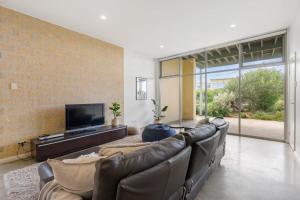 ein Wohnzimmer mit einem Ledersofa und einem TV in der Unterkunft Samphire Middleton-Beach - BYO Linen - Wi-Fi-Luxury-Family in Middleton