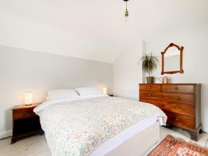a bedroom with a bed with a dresser and a mirror at Oasis Cottage in Broughton Gifford