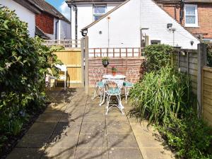 un patio con mesa, sillas y una valla en New Street Cottage, en Lydd