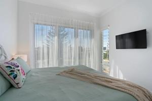 a white bedroom with a bed and a flat screen tv at 5 Tabernacle Rd Encounter Bay- No Linen Included in Encounter Bay +40 photos