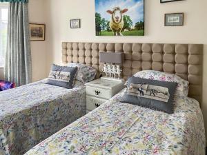 1 dormitorio con 2 camas y una foto de oveja en la pared en Walnut Cottage en Long Melford