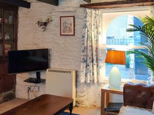 a living room with a television and a couch and a table at Talland House in Polperro