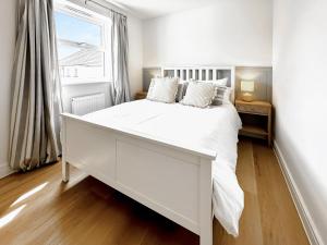 a white bedroom with a large white bed and a window at Burrows Ridge in Appledore