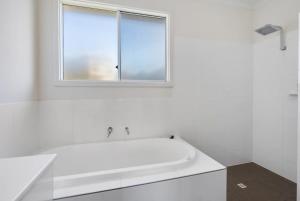 a white bathroom with a tub and a window at 8 Davies St Encounter Bay - No Linen Included - Wi-Fi - Sea Views in Encounter Bay +38 photos
