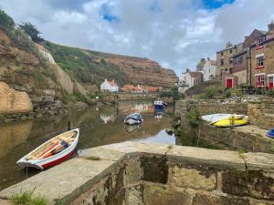 two boats are docked in a river next to buildings at Pilot Me Cottage in Staithes