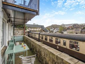 a table and chairs on a balcony with a train at Dee Bank Cottage in Llangollen