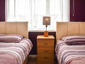 um quarto com 2 camas e um candeeiro numa cómoda em 21 Hillside em Mundesley