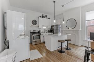 Una cocina blanca con encimera y taburetes. en Housepitality - The Short North Getaway, en Columbus