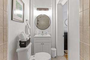 a white bathroom with a toilet and a mirror at Housepitality - The Short North Getaway in Columbus