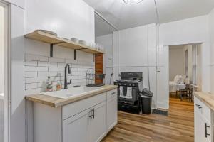 a white kitchen with a sink and a stove at Housepitality - The City Gateway in Columbus