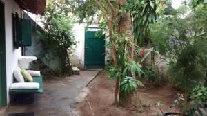 a garden with a green door and a green chair at Casa da Dona Dita in Paraty