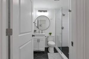 a white bathroom with a toilet and a mirror at Housepitality - The Short North Sanctuary in Columbus