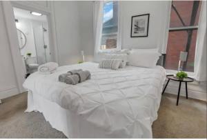 a white bedroom with a large white bed with two pillows at Housepitality - The Short North Sanctuary in Columbus