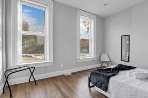 um quarto com uma cama e duas janelas em Housepitality - The Capital House - 5 BR Downtown em Columbus