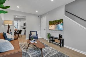 a living room with a couch and a tv on a wall at The Schumacher Townhouse - 2 BR in Columbus