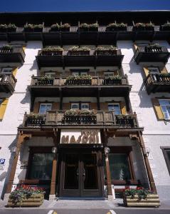 un edificio con macetas y balcones. en Hotel Majoni en Cortina dʼAmpezzo