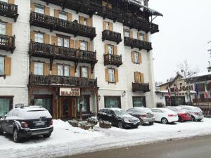 un edificio con coches aparcados frente a él en la nieve en Hotel Majoni, en Cortina dʼAmpezzo