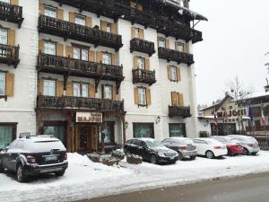 ein Gebäude mit Autos, die vor ihm im Schnee geparkt sind in der Unterkunft Hotel Majoni in Cortina d'Ampezzo