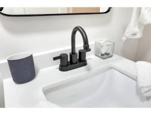 a bathroom sink with a black faucet and a cup at Housepitality - The Cobblestone 2- New Renovation in Columbus