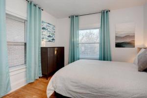 1 dormitorio con 1 cama y 2 ventanas con cortinas azules en Housepitality - The Maynard Manor en Columbus