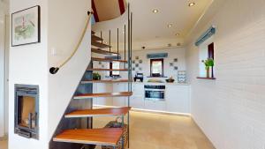 a staircase in a kitchen with white walls and wooden benches at Lütje Hüs 2 in Hörnum