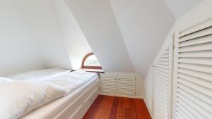 a white bedroom with a bed and a window at Lütje Hüs 2 in Hörnum