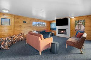 sala de estar con sofá, sillas y chimenea en Tasman Holiday Parks - Rotorua en Rotorua