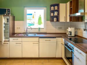 eine Küche mit weißen Schränken, einem Waschbecken und einem Fenster in der Unterkunft Ferienhaus Seemannsruh Wohnung mit Wasserblick und abgeschlossenem Grundstück in Marienfelde