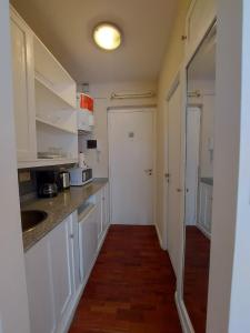 a kitchen with white cabinets and a sink and a door at Hermoso Departamento monoambiente, excelente ubicación a 50 mts de Plaza principal in Salta