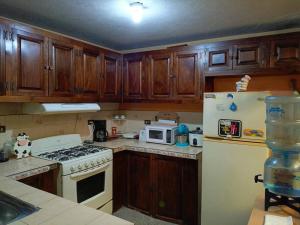 a kitchen with wooden cabinets and a stove and a refrigerator at Casa completa en Xela in Quetzaltenango
