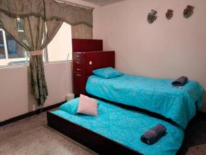 1 dormitorio con 2 camas con sábanas azules y ventana en Casa completa en Xela, en Quetzaltenango