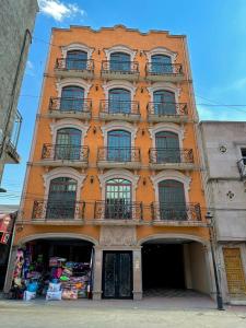 a tall orange building with windows and balconies at Hotel Hacienda el Edén in San Juan de los Lagos